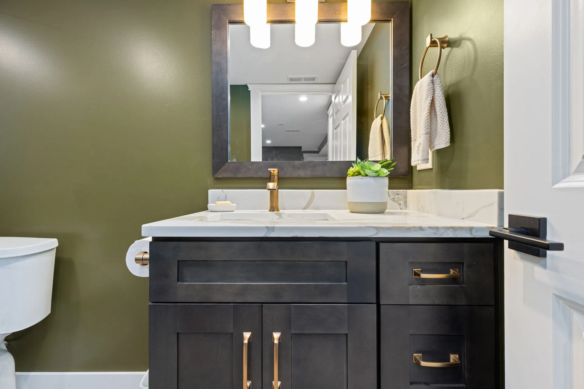 Basement vanity with olive walls, dark wood cabinetry and brass fixtures