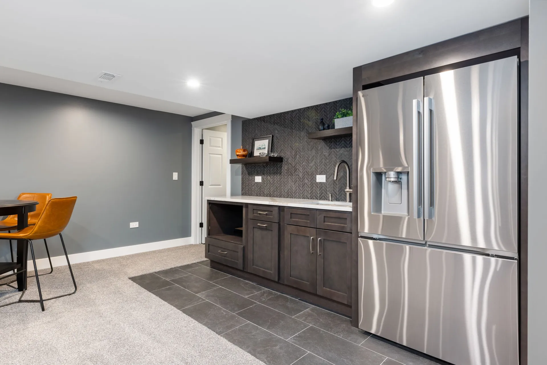 Basement wet bar with chevron slate tile and dark stained cabinets