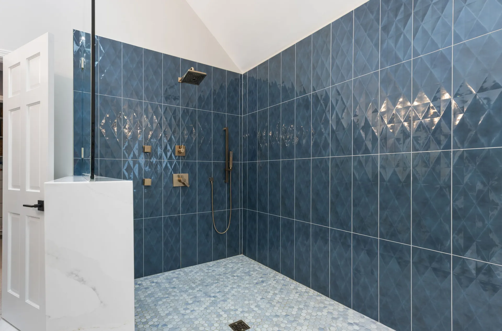 Walk-in shower with blue diamond tile and brass fixtures from a Naperville remodel