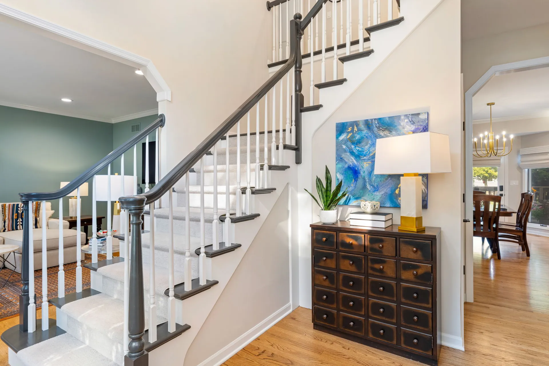 Foyer staircase with apothecary console and abstract blue art