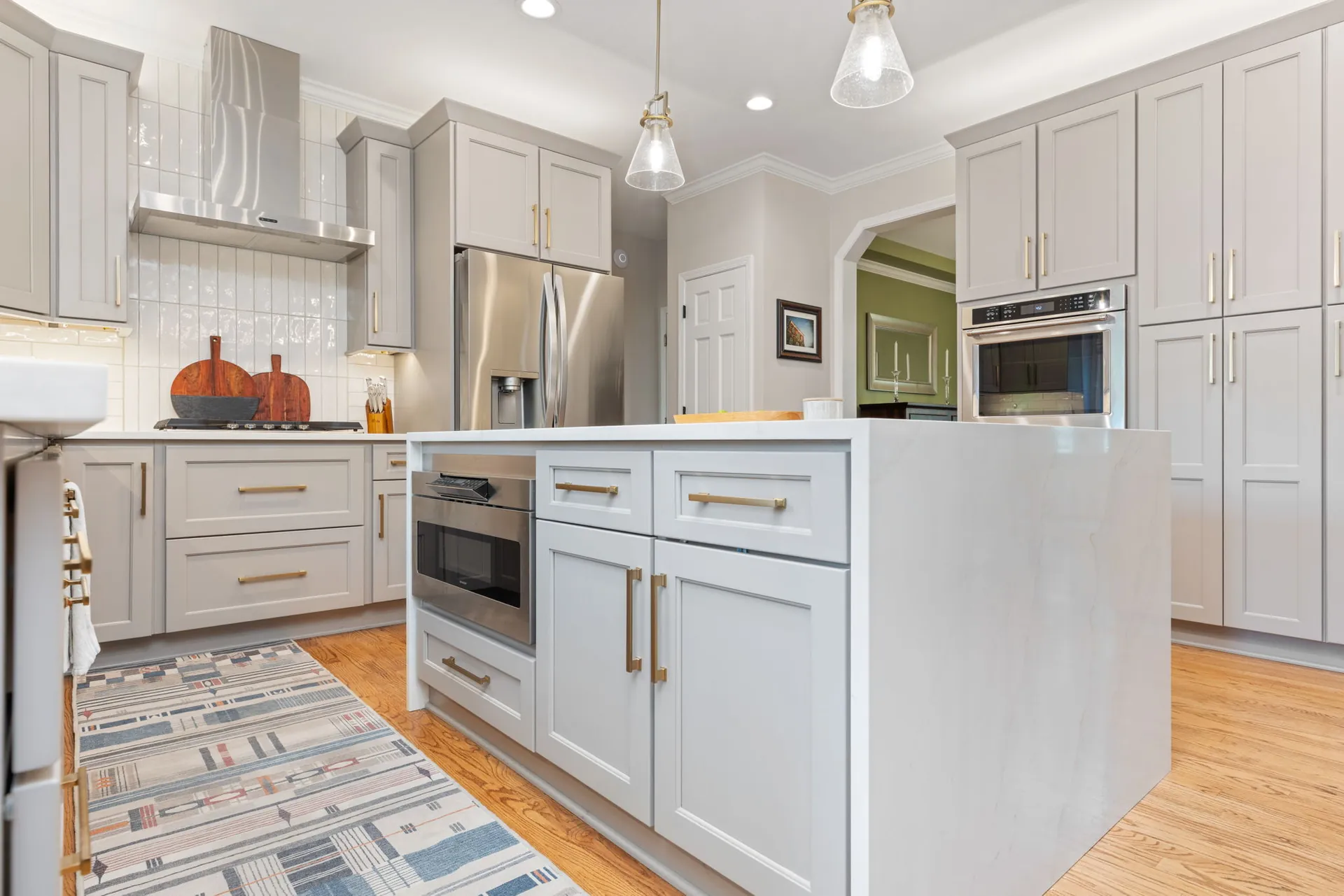Gray kitchen island with built-in microwave drawer and brass pulls