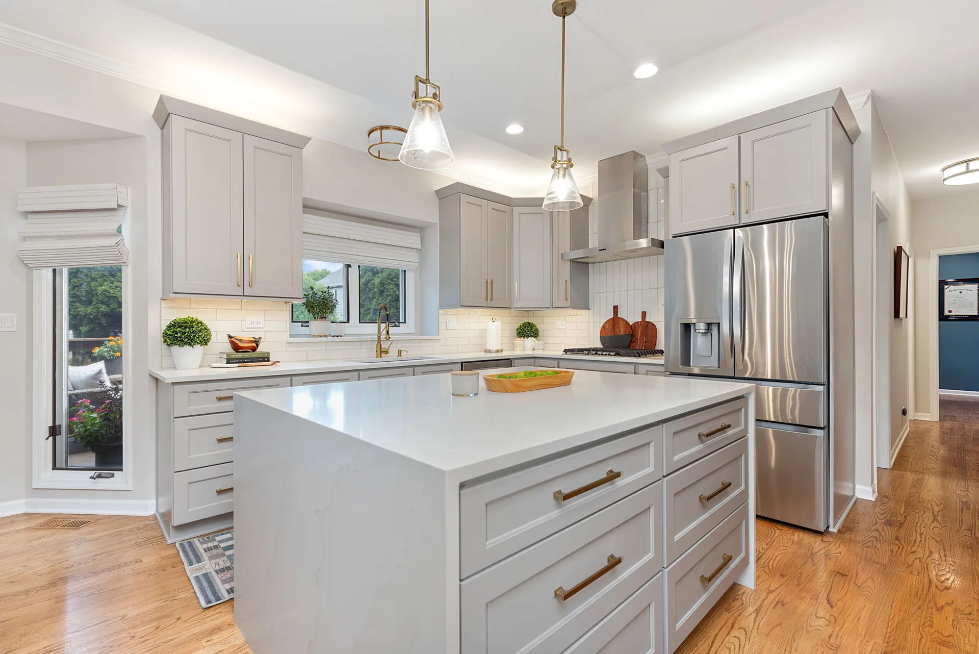 Gray shaker kitchen with waterfall quartz island and brass pulls