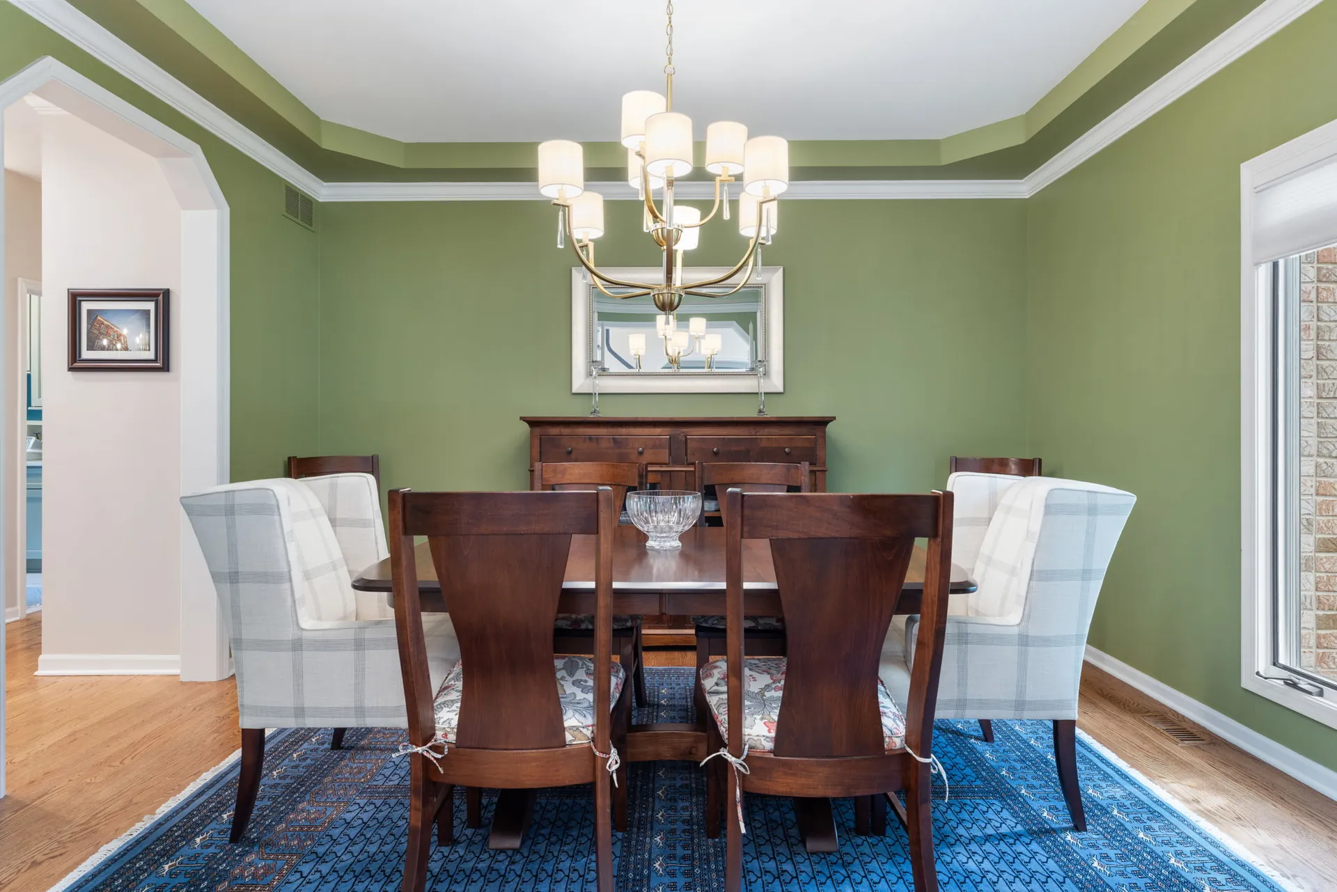 Green dining room with tray ceiling and brass chandelier