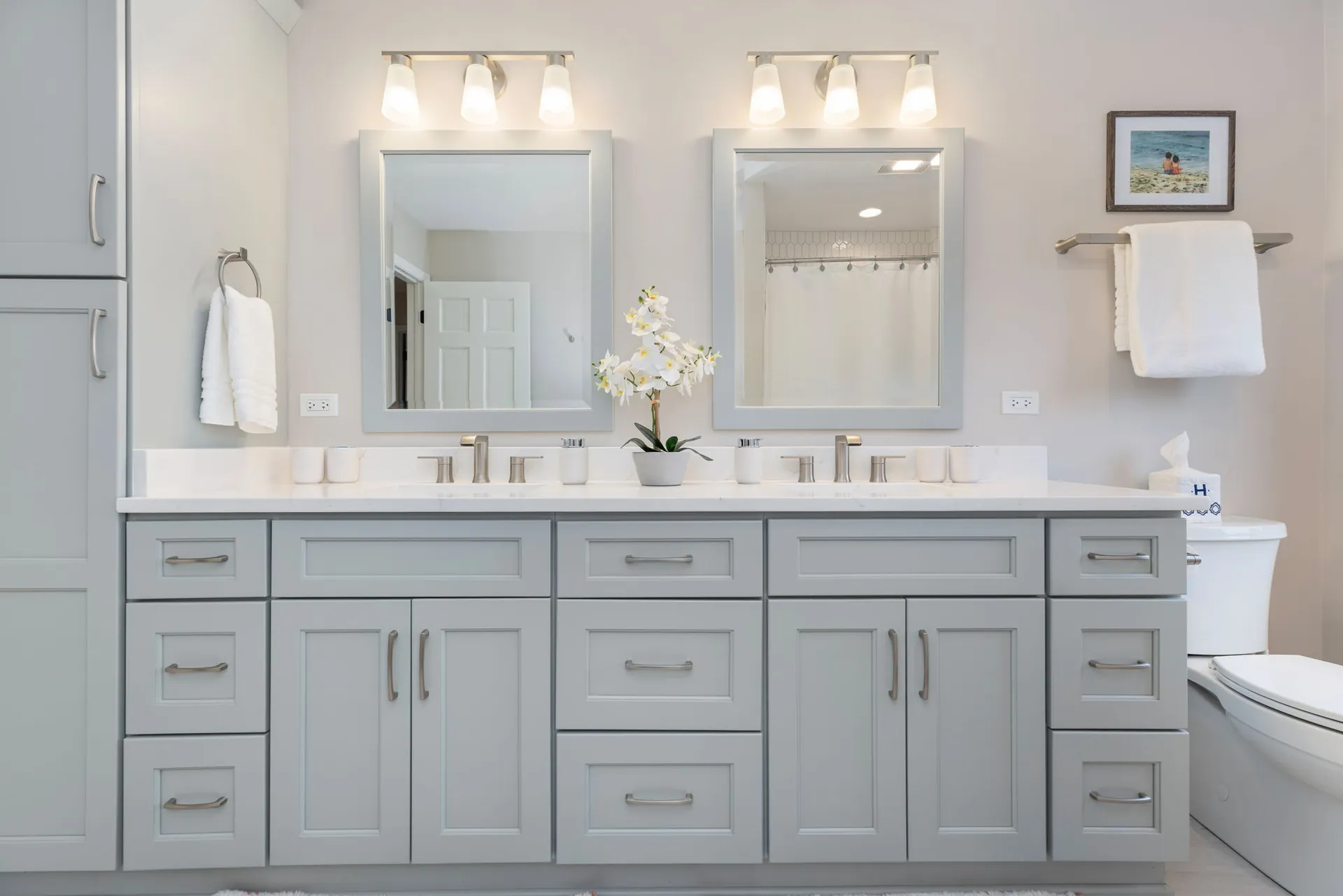 Light gray double vanity with framed mirrors and sconces